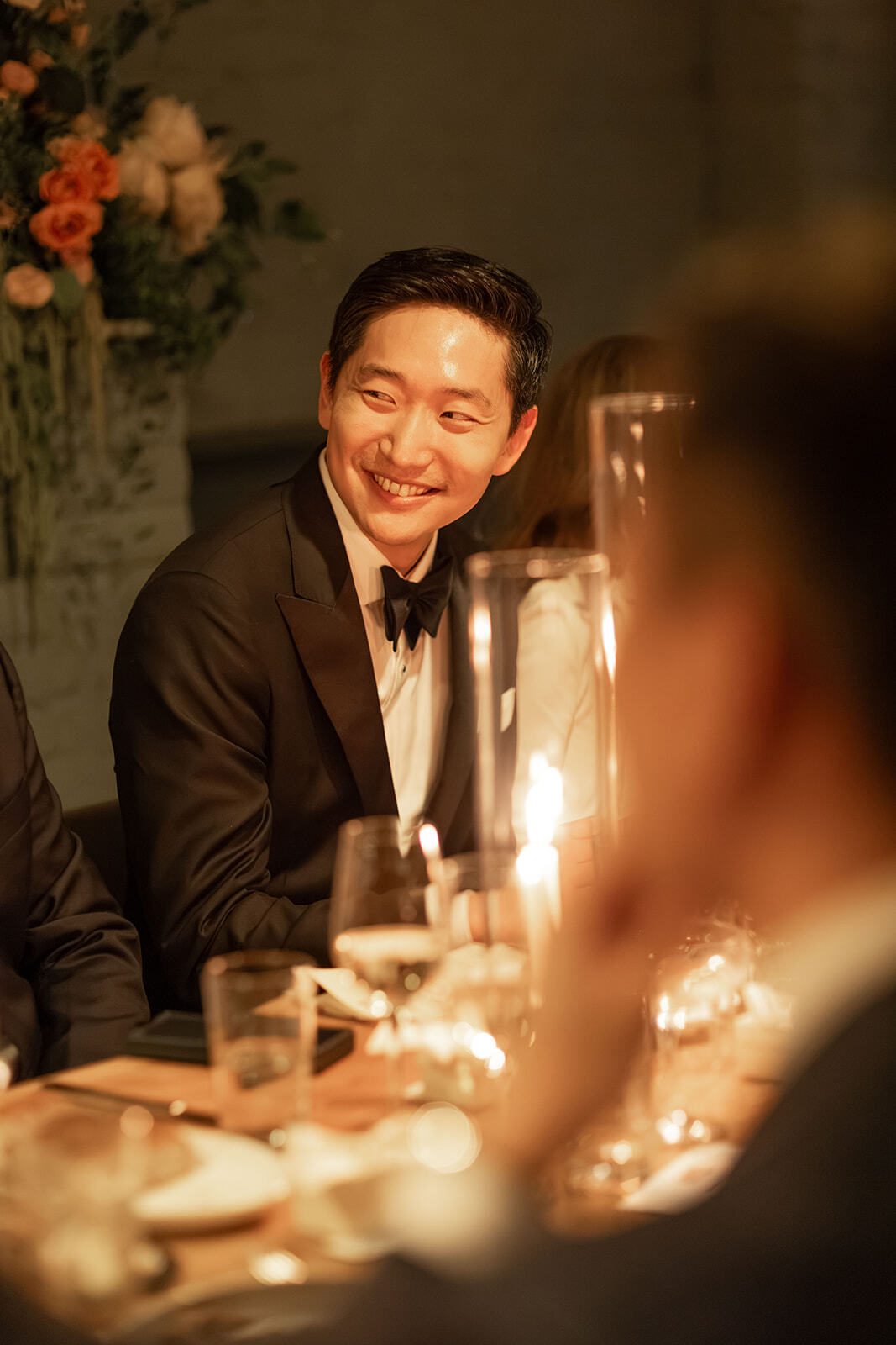 Smiling guest in a tuxedo at the candlelit wedding dinner, Adena and Brian's wedding, by Brooklyn wedding photographer Lana Dubkova.
